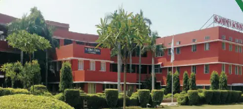 The red-brick school building behind clipped hedges and palms