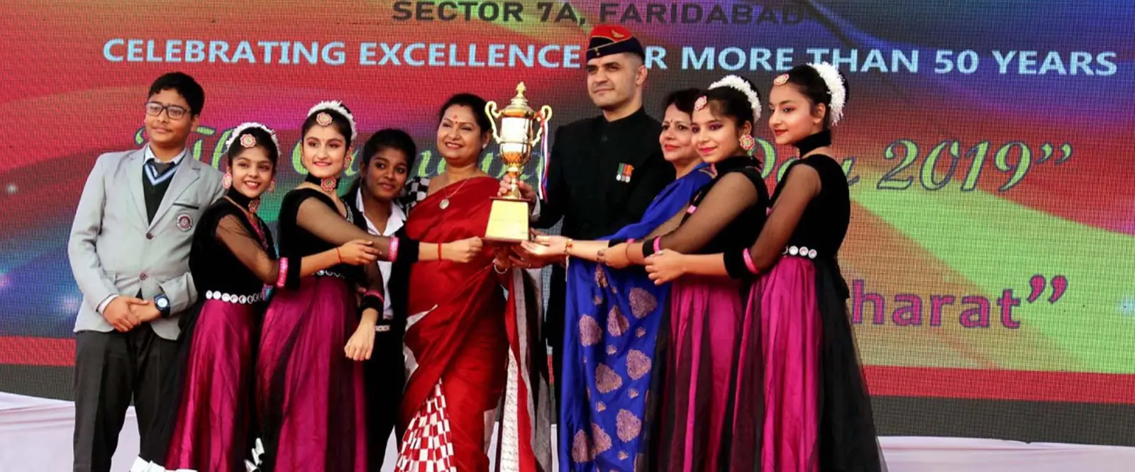 Students and teachers holding up a trophy on stage